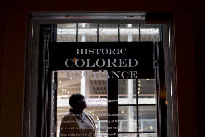 Image: A woman stands in the old doorway of the Lyric Theatre, in Birmingham, Ala. Courtesy of Global News and AP, photo by Brynn Anderson